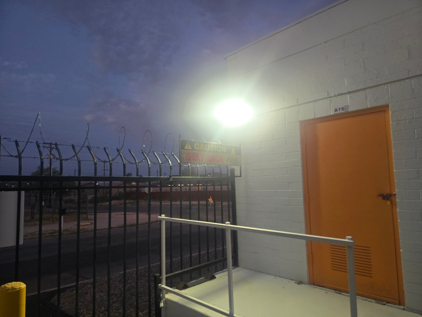 Floodlit gate and razor-wire perimeter at the Tucson facility after dark